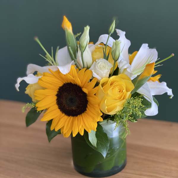 Sunflower and yellow rose bouquet in a glass vase