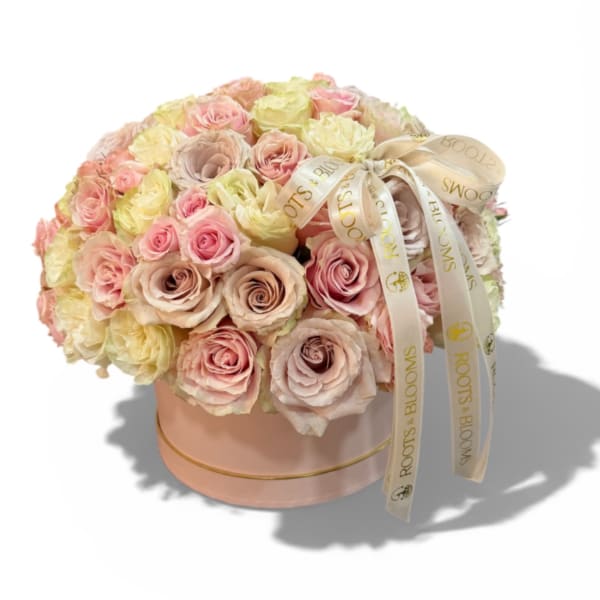 Round bouquet of pastel roses in a pink hat box with ribbon