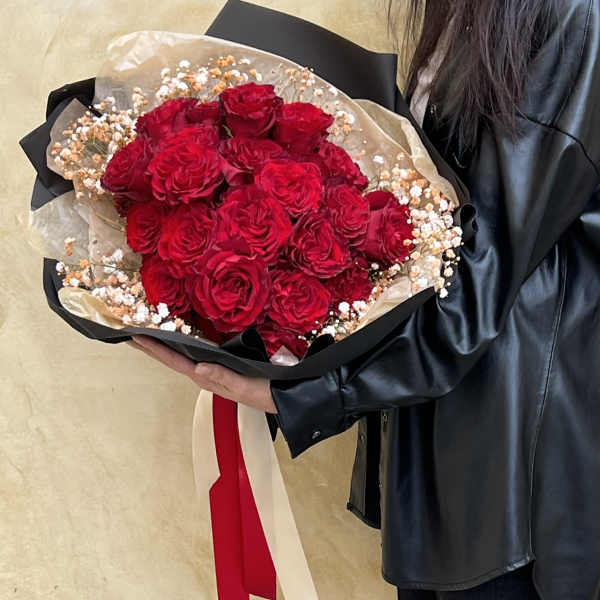 Large bouquet of red roses with baby's breath wrapped in black paper