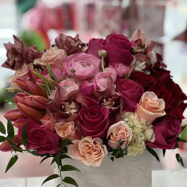 Pink and magenta roses with orchids in a white box