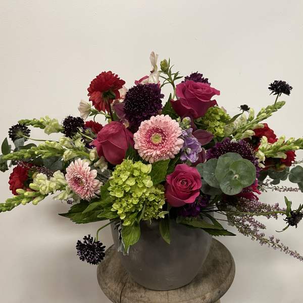 Mixed bouquet of pink roses, gerbera daisies, and green hydrangea in a gray vase