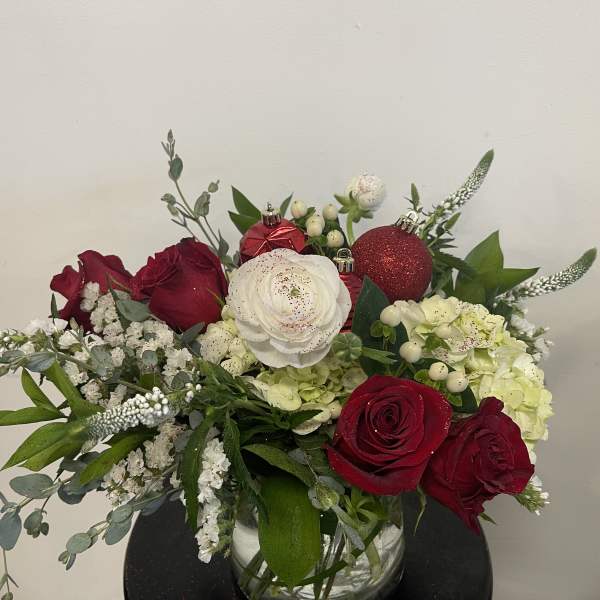 Red and white roses with hydrangeas in a glass vase, accented with ornaments