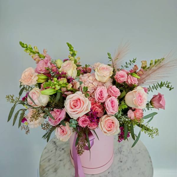 Pink and cream rose bouquet in a pink hat box with a ribbon