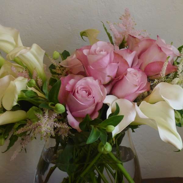 Pink roses and white calla lilies in a glass vase