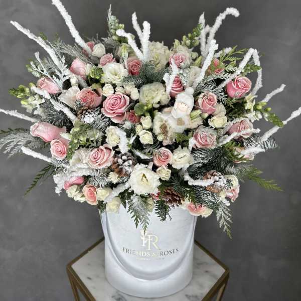 Pink and white roses in a white hatbox with frosted winter accents