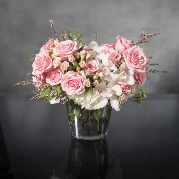 Pink roses and white orchids arranged in a glass vase