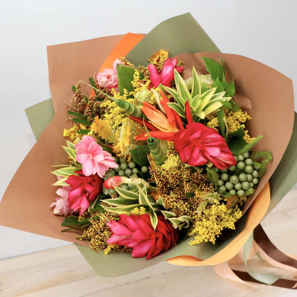 Bouquet of bright tropical flowers wrapped in brown and green paper