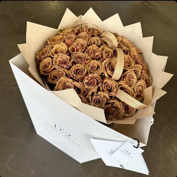 Bouquet of tan roses wrapped in white paper with ribbon