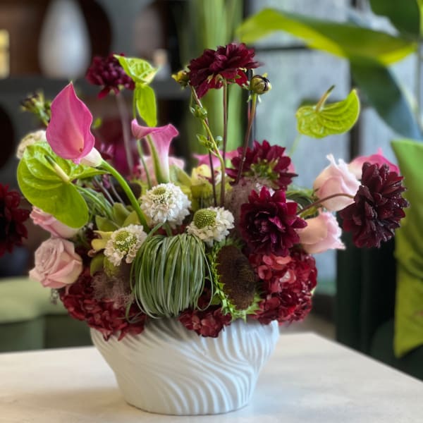 Pink and burgundy floral arrangement in a white vase