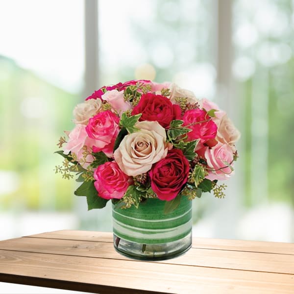 Pink and red roses arranged in a glass vase