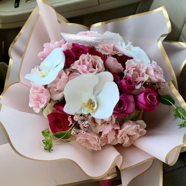 Pink and red rose bouquet with white orchids in pale wrapping