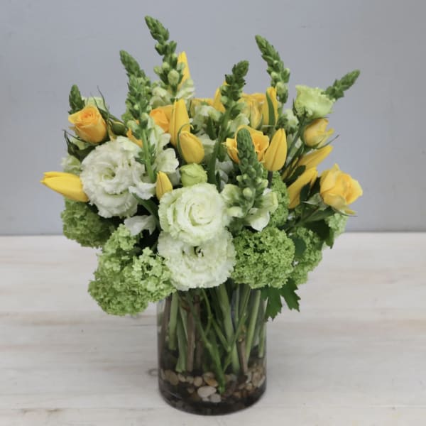 Yellow roses and white blooms in a glass vase