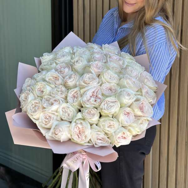 Large bouquet of pale pink and white roses wrapped in pink paper