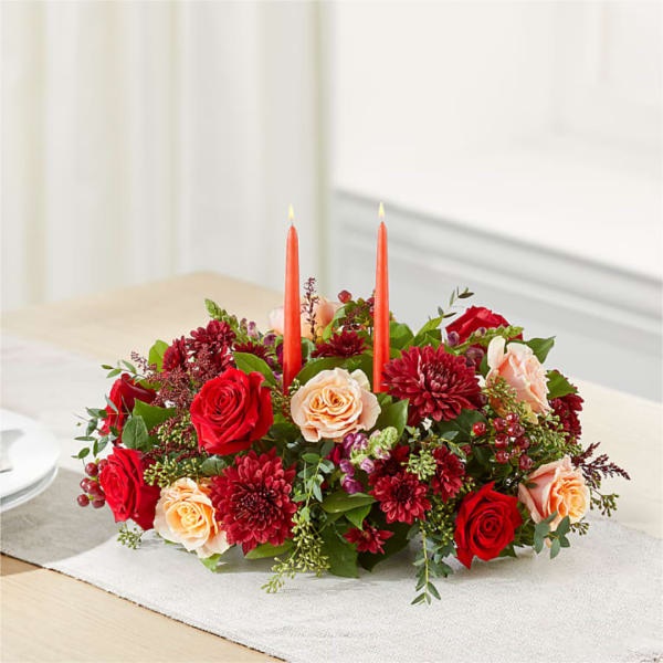 Low floral centerpiece with red and peach roses and two orange candles