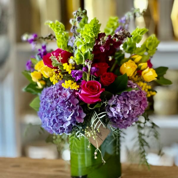 Colorful bouquet of roses, hydrangeas, and snapdragons in a glass vase