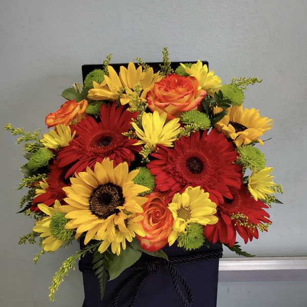 Bright mixed bouquet of red and yellow flowers in a black gift box