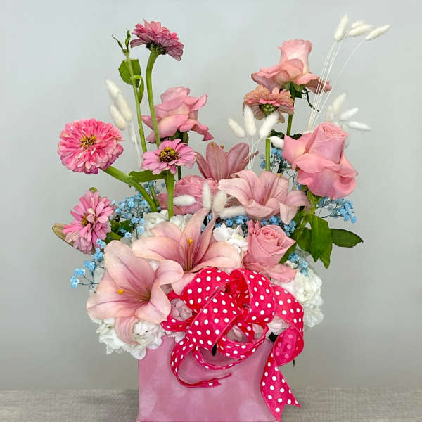 Pink floral arrangement in a pink box with a polka-dot ribbon