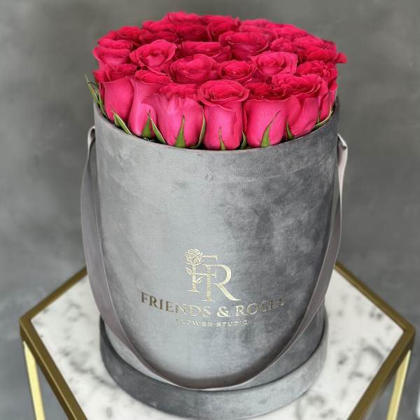 Hot pink roses arranged in a gray round hat box