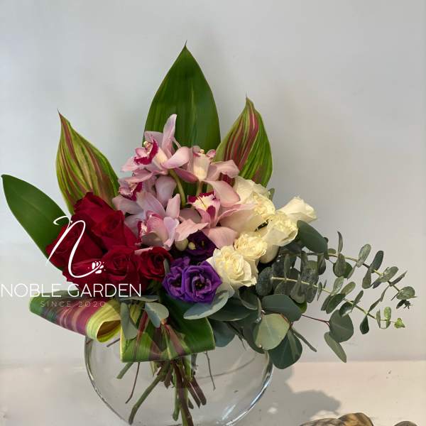 Mixed bouquet of roses and orchids in a glass vase