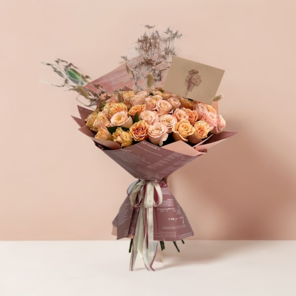 Bouquet of peach and blush roses wrapped in mauve paper
