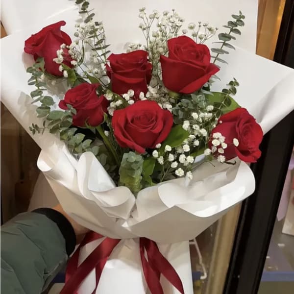 Bouquet of red roses with white baby's breath wrapped in white paper
