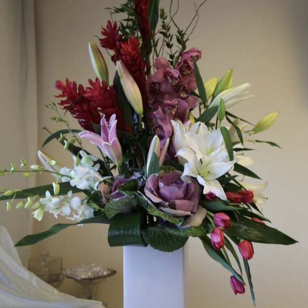 Tall mixed floral arrangement in a white rectangular vase