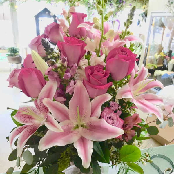 Pink roses and lilies arranged in a clear glass vase
