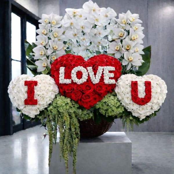 Heart-shaped rose arrangement with white orchid sprays and floral letters
