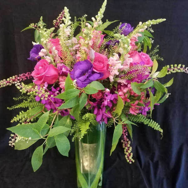 Bouquet of pink and purple flowers in a tall glass vase