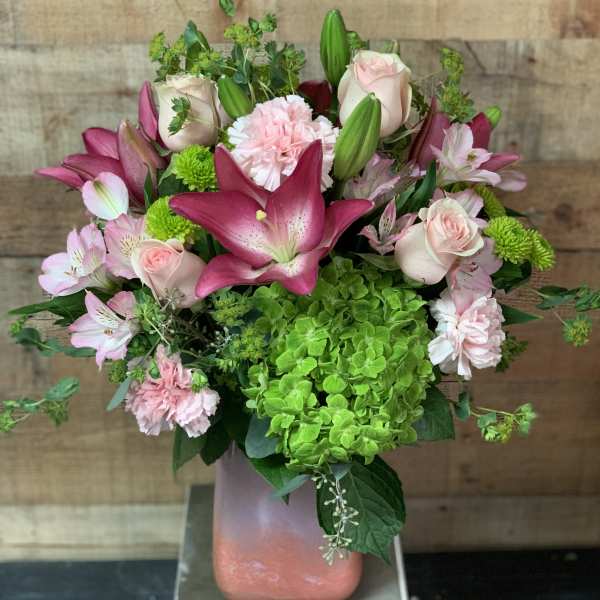 Pink lilies, roses, carnations, and green hydrangea in a vase