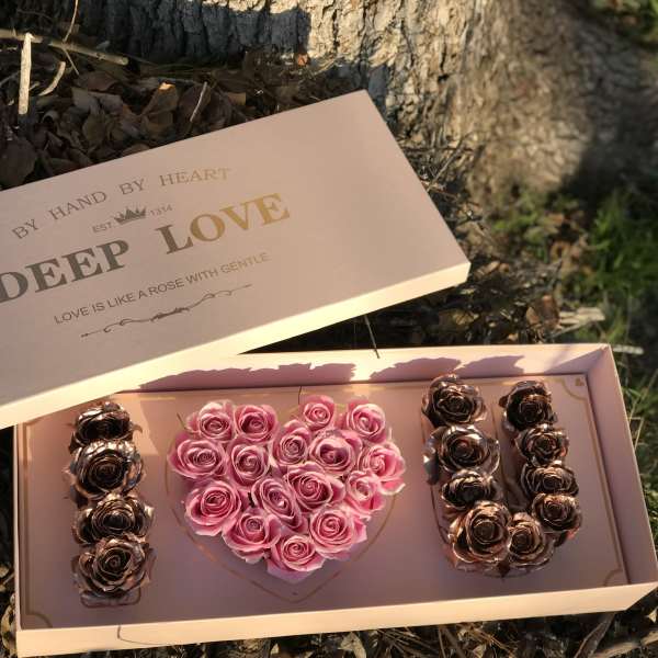 Pink rose arrangement in a heart-shaped box with gold roses on the sides