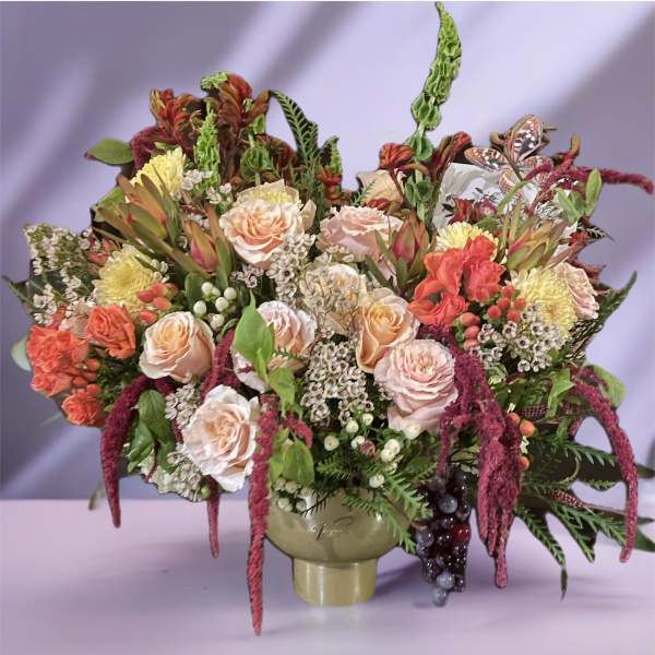 Large bouquet of peach and pink roses in a vase with mixed foliage