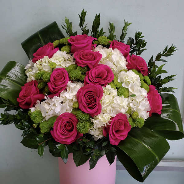 Pink roses and white hydrangeas in a pink box with green accents