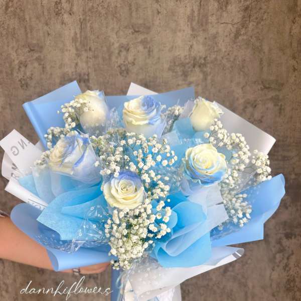 Bouquet of white roses with baby's breath wrapped in blue paper
