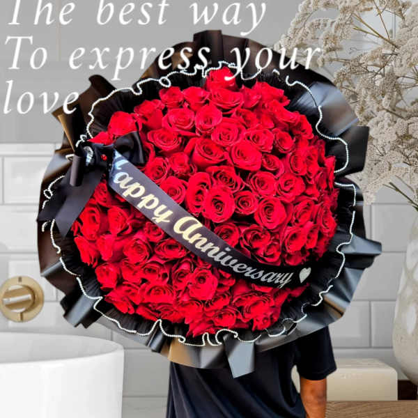 Large bouquet of red roses wrapped in black paper with a "Happy Anniversary" ribbon