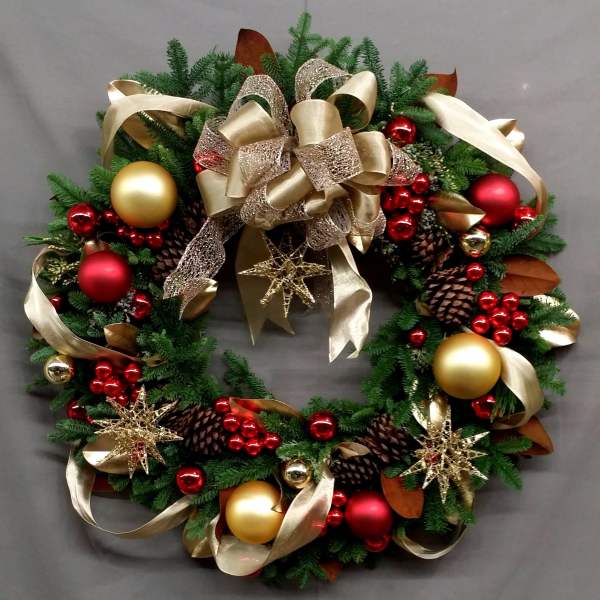 Christmas wreath with gold ribbon, red ornaments, and pinecones