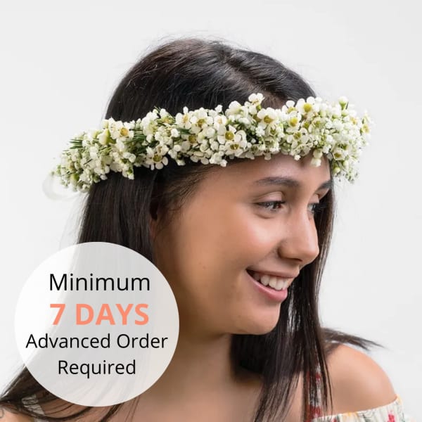 White floral crown worn by a smiling woman against a light background