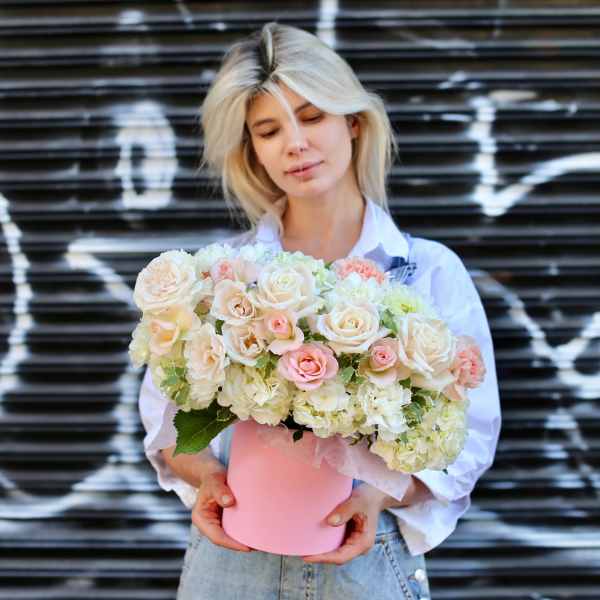 Woman holding a pink box of pale roses and hydrangeas