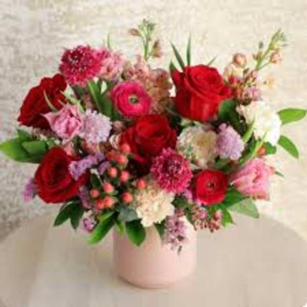 Bouquet of red and pink flowers in a pale pink vase