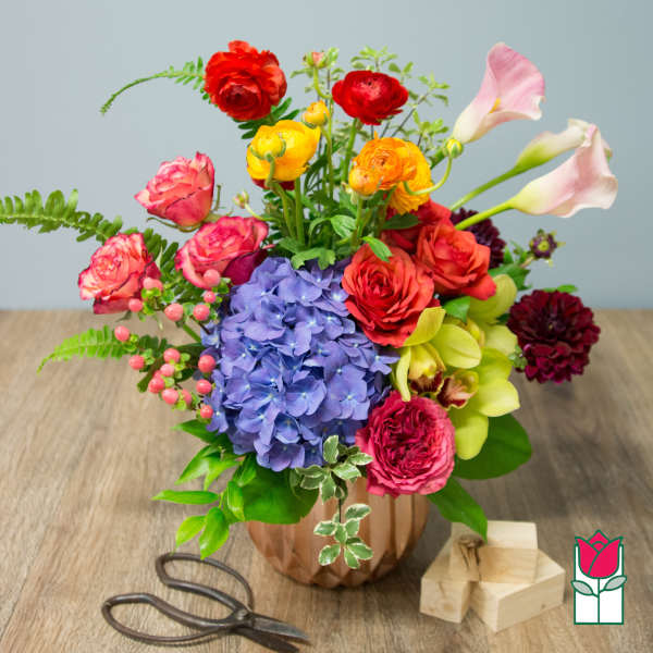 Colorful mixed bouquet in a copper vase with calla lilies and roses