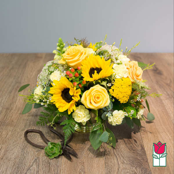 Yellow roses and sunflowers in a low glass vase with a ribboned succulent accent