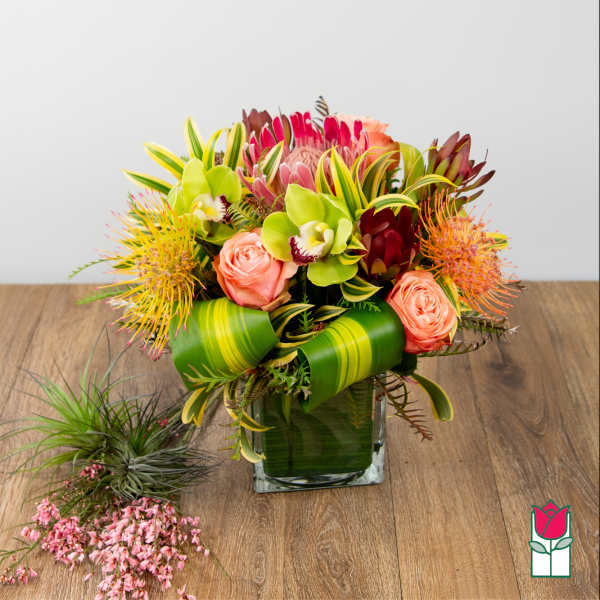 Tropical bouquet with pink roses and green orchids in a glass vase