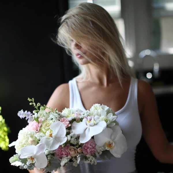 Woman holding a pastel bouquet with white orchids and pink flowers