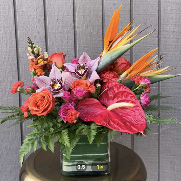 Tropical bouquet with orchids, roses, anthurium, and bird of paradise in a glass vase