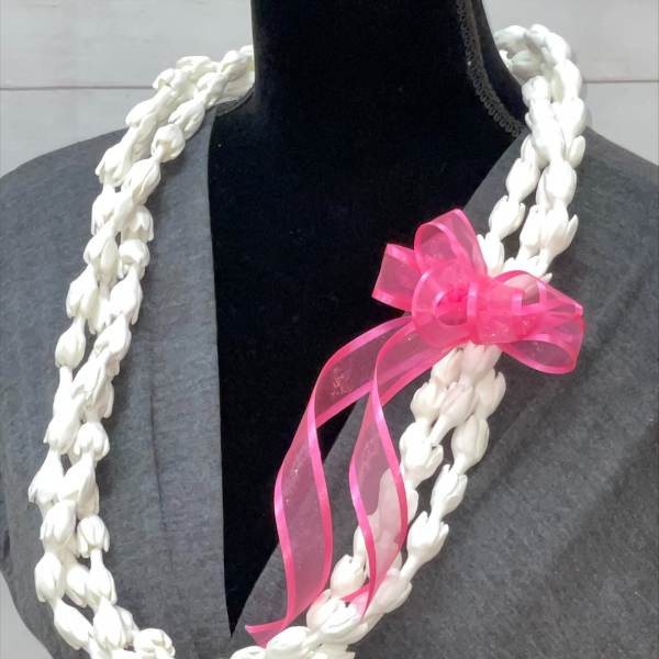 Double-strand white floral lei with a pink ribbon bow displayed on a mannequin