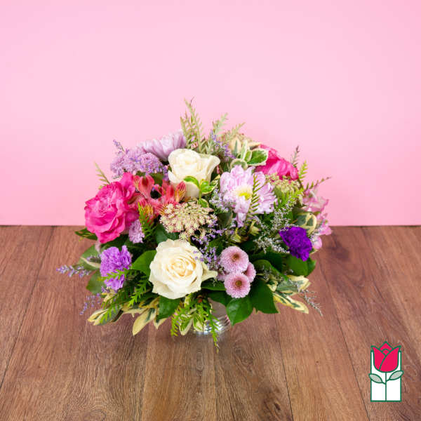Mixed pink, white, and purple flower arrangement in a clear glass vase