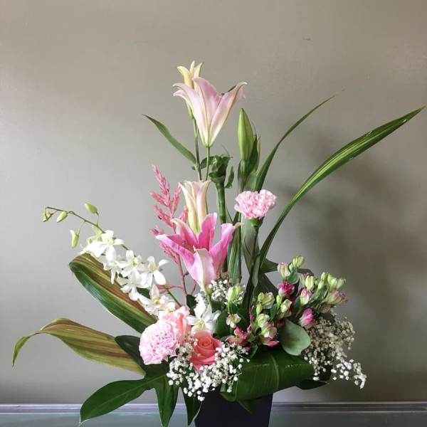 Pink and white floral arrangement in a black vase with tall lilies