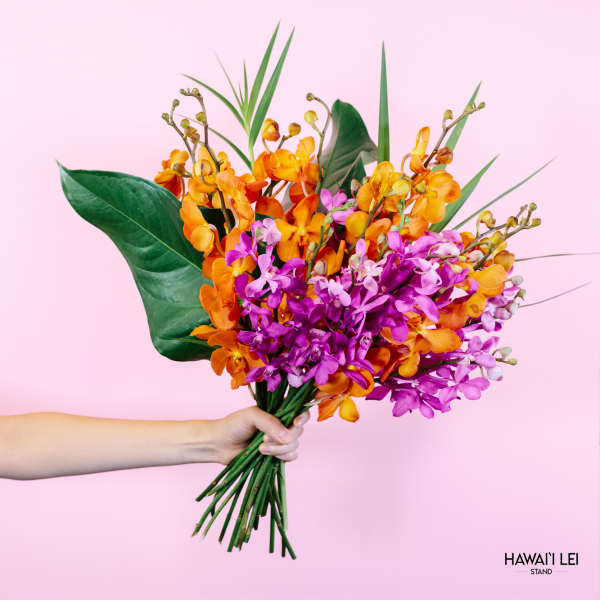 Handheld bouquet of orange and purple orchids against a pink background
