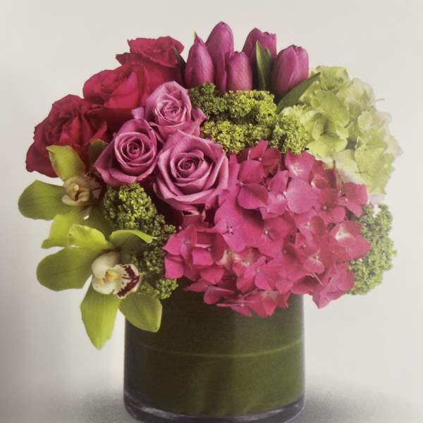 Pink and purple floral arrangement in a dark glass vase