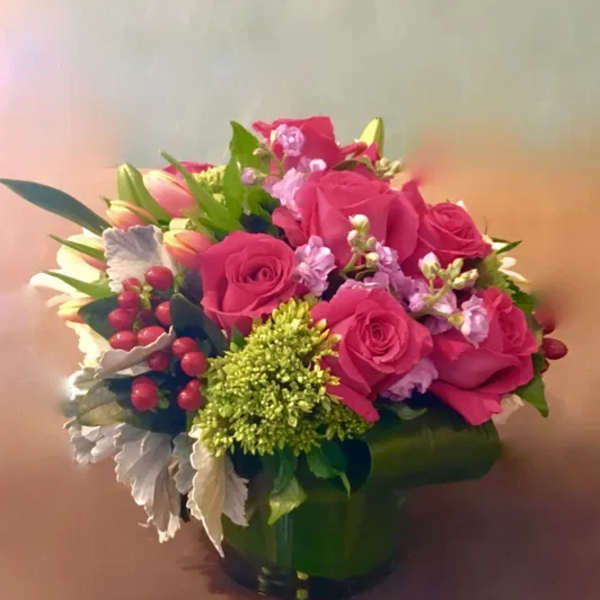 Pink roses and tulips arranged in a green vase